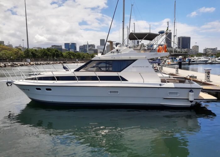 Lancha Oceanic 36 SB atracada em marina, vista lateral, com prédios da cidade ao fundo