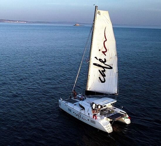 Catamarã Lagoon 380 S2 navegando em mar aberto ao entardecer, oferecendo uma experiência relaxante e confortável para os passageiros.