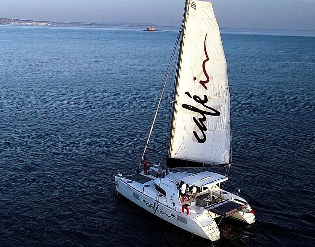 Catamarã Lagoon 380 S2 navegando em mar aberto ao entardecer, oferecendo uma experiência relaxante e confortável para os passageiros.