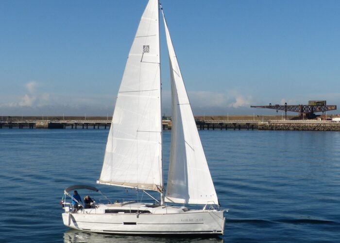 Veleiro Dufour 360 em pleno movimento, com suas velas abertas e tripulantes a bordo.