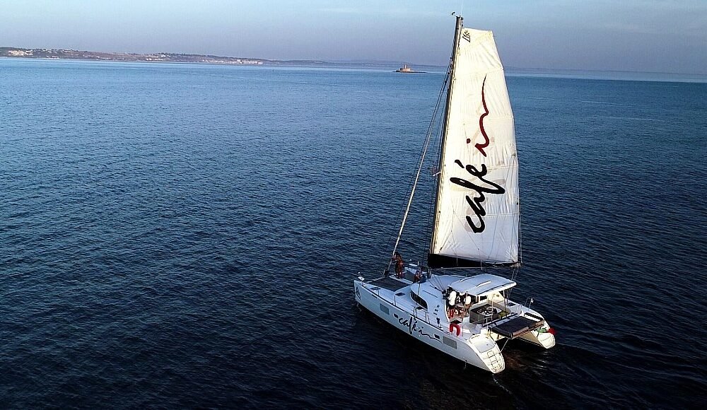Catamarã Lagoon 380 S2 navegando em mar aberto ao entardecer, oferecendo uma experiência relaxante e confortável para os passageiros.