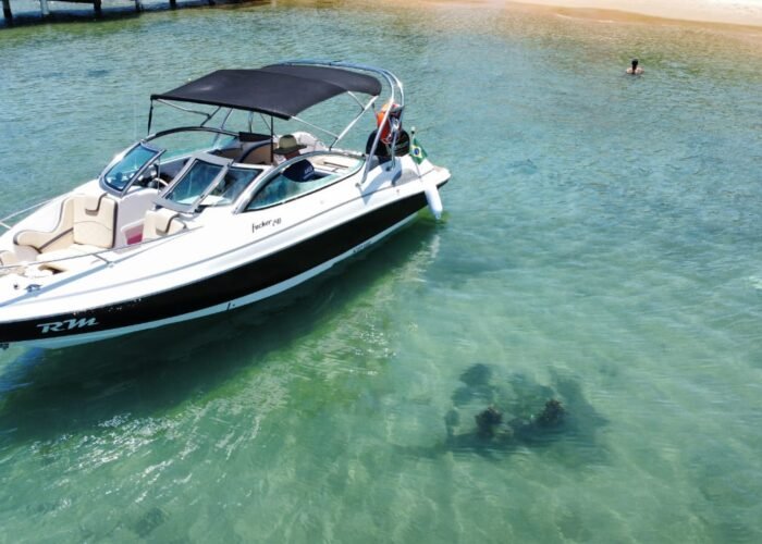 Lancha Focker 240 Open ancorada em praia de águas cristalinas em Búzios, ideal para passeio privativo.