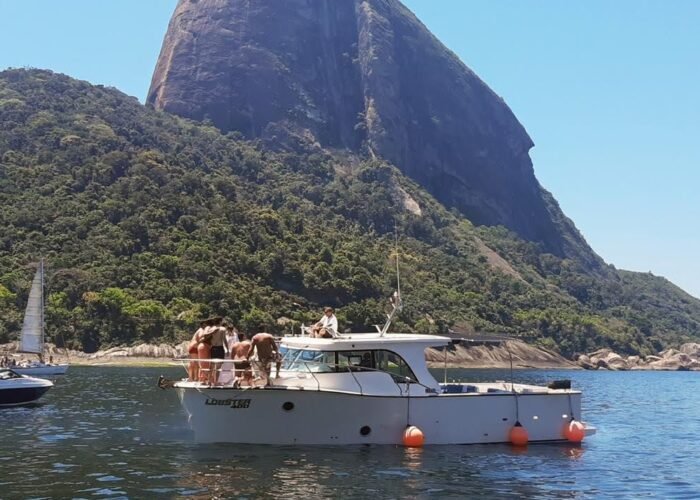 lancha Lobster 400 ancorada diante do Pão de Açúcar, com grupo na proa e outros barcos ao redor