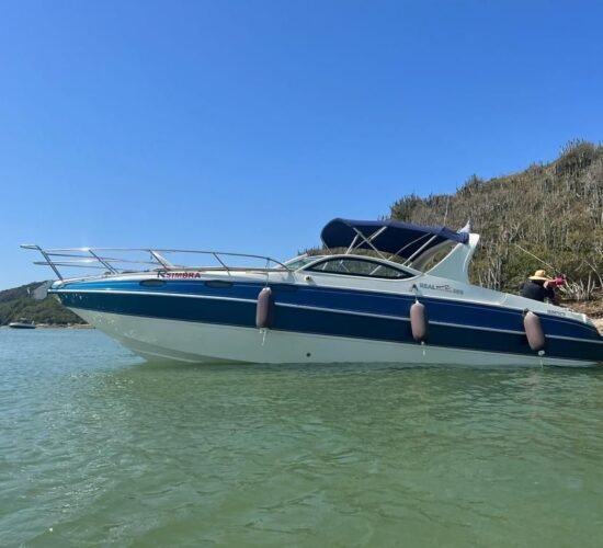 Lancha Real Powerboat 30 pés ancorada em águas claras, com vegetação ao fundo.