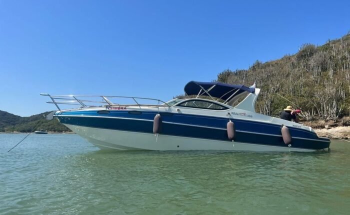 Lancha Real Powerboat 30 pés ancorada em águas claras, com vegetação ao fundo.