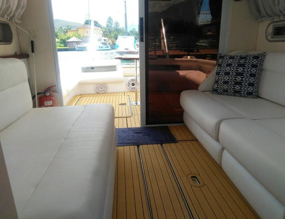 Salão interno da Lancha Oceanic 32 em Angra dos Reis, com estofados brancos e decoração aconchegante, ideal para relaxar.