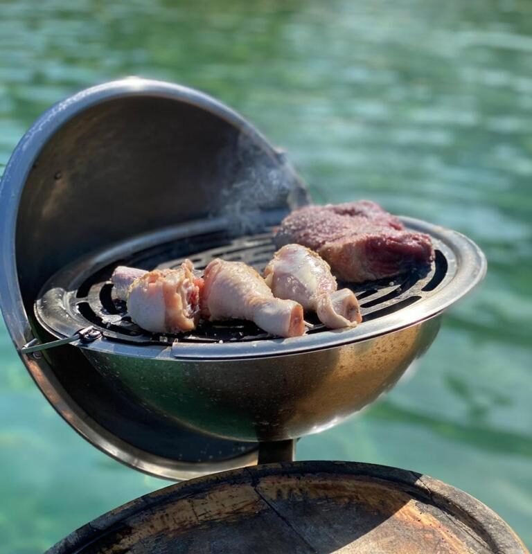 Churrasqueira portátil a bordo da Lancha Oceanic 32 em Angra dos Reis, com carnes grelhando durante um passeio de barco privativo.