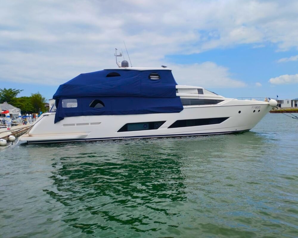 Iate Ferretti 850 em marina de Angra dos Reis, disponível para aluguel de lancha com capa azul protetora instalada.