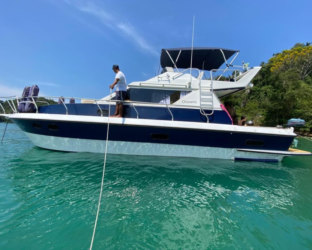 Lateral da Lancha Oceanic 32 navegando em águas verdes de Angra dos Reis, destacando design e espaço para passeio de barco exclusivo.