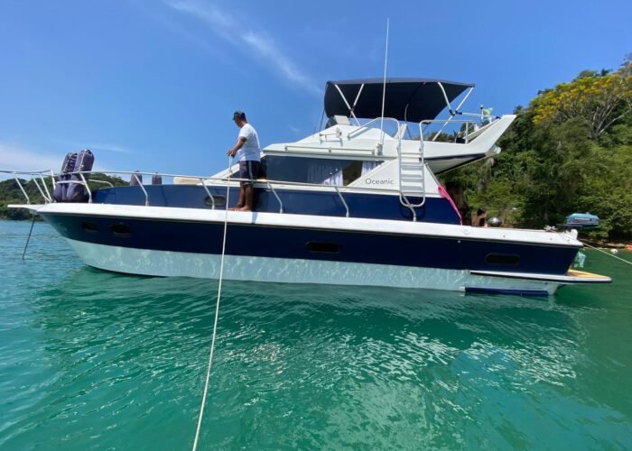 Lateral da Lancha Oceanic 32 navegando em águas verdes de Angra dos Reis, destacando design e espaço para passeio de barco exclusivo.