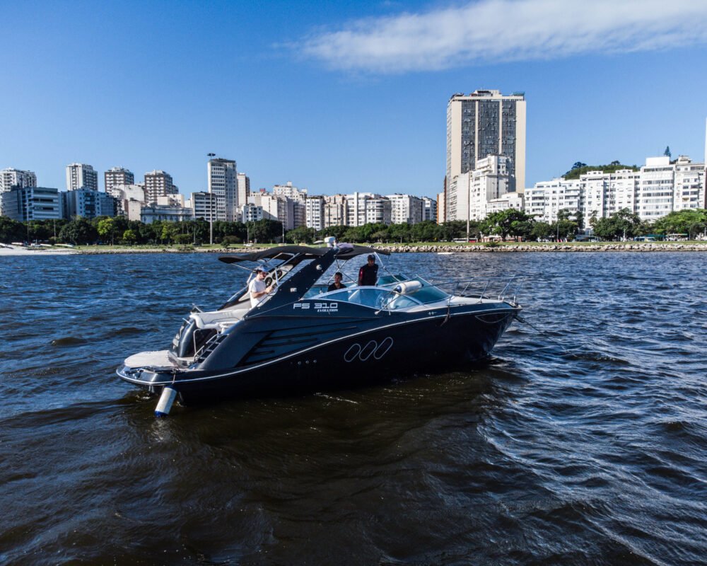 Lancha FS 310 em navegação na Baía de Guanabara, com prédios e o horizonte do Rio de Janeiro ao fundo.