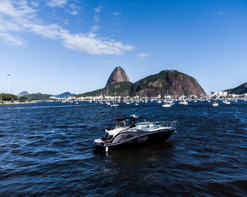 Lancha FS 310 navegando com vista para o Pão de Açúcar e águas calmas da Baía de Guanabara.