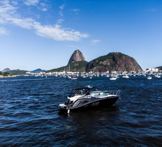 Lancha FS 310 navegando com vista para o Pão de Açúcar e águas calmas da Baía de Guanabara.