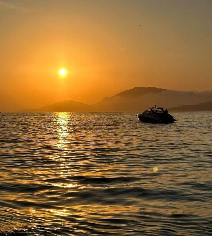 Lancha AZOV Z380s ancorada durante o pôr do sol com reflexo dourado na água.