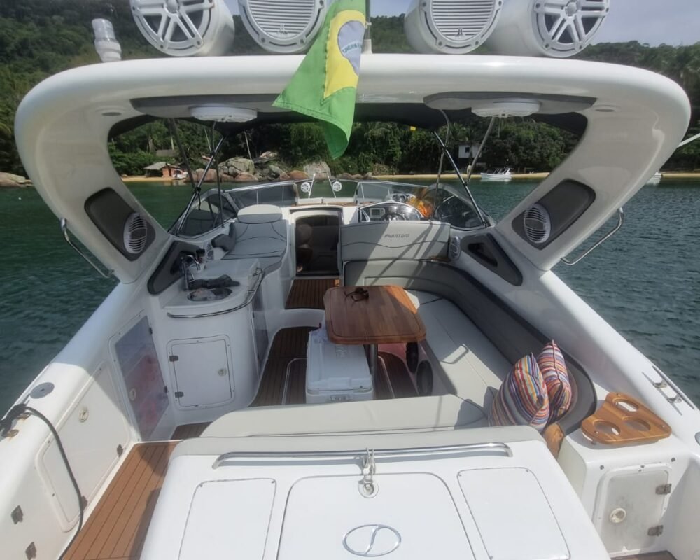 Vista da área traseira da lancha Phantom 290 com acabamento em madeira e bandeira do Brasil em Angra dos Reis.