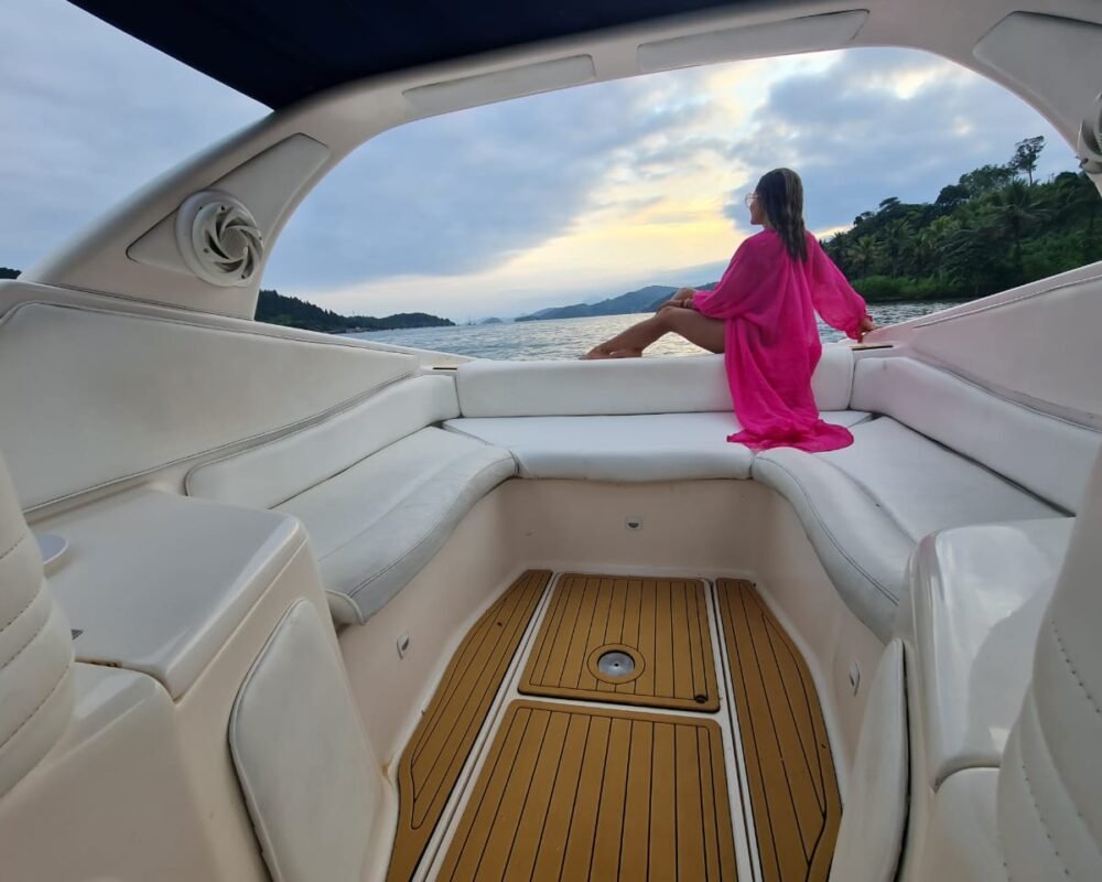 Mulher apreciando a vista em um passeio de lancha Runner 29, com assentos confortáveis e deck de madeira em Angra dos Reis.