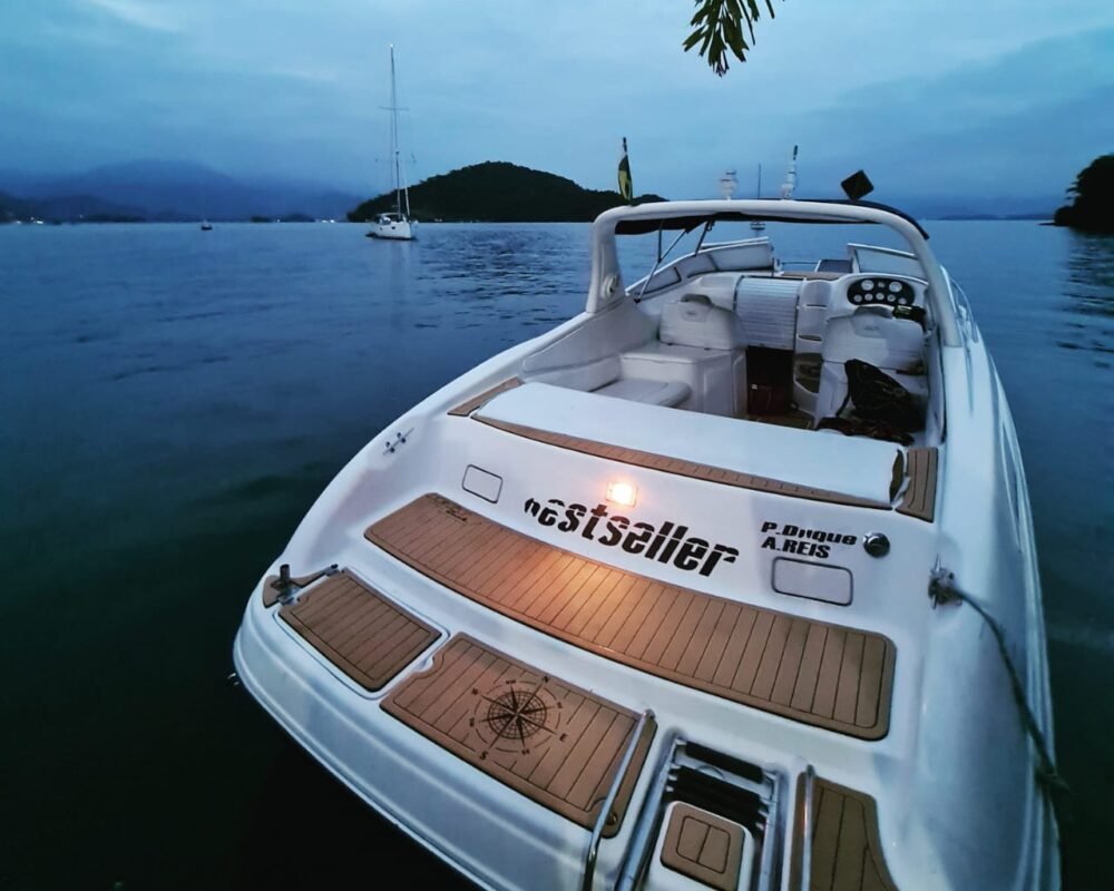 Vista traseira da lancha Runner 29 ancorada em Angra dos Reis, com iluminação destacando o deck e a área de lazer.