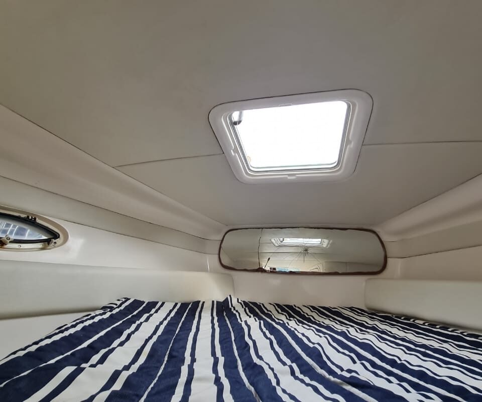 Interior da cabine da lancha Runner 29 com cama confortável, disponível para passeios privativos em Angra dos Reis.