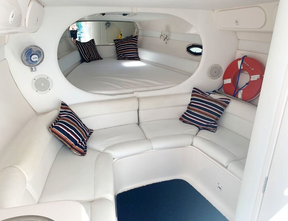 Interior da cabine da Lancha Runner 38 com decoração confortável e vista externa.