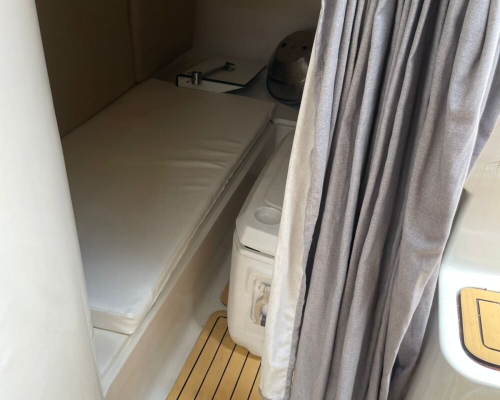 Cabine adicional na lancha Runner 410, com cama e cortina para privacidade, ideal para um passeio de lancha exclusivo.