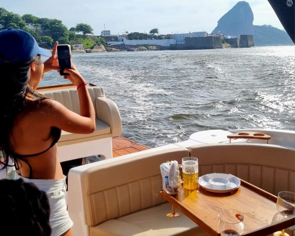 Passageira fotografando o Forte de São João e o Pão de Açúcar a bordo da lancha Coral 26.