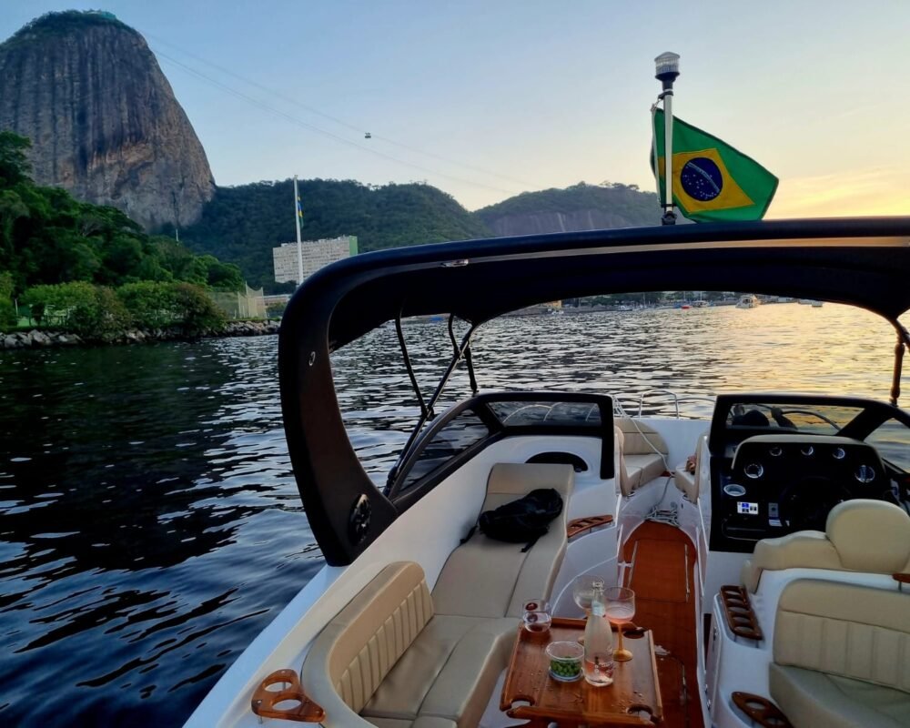 Lancha Coral 26 navegando próximo ao Pão de Açúcar, com a bandeira do Brasil ao vento.