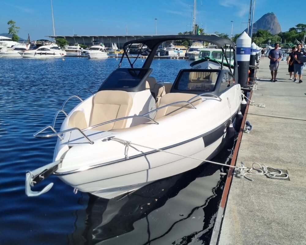 Lancha Coral 26 ancorada na Marina da Glória, com o Pão de Açúcar ao fundo em um dia ensolarado.