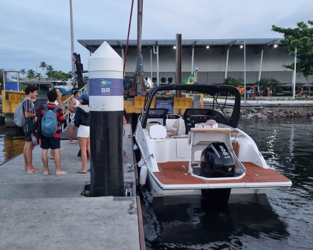 Lancha Coral 26 atracada em um píer, com passageiros se preparando para embarcar.