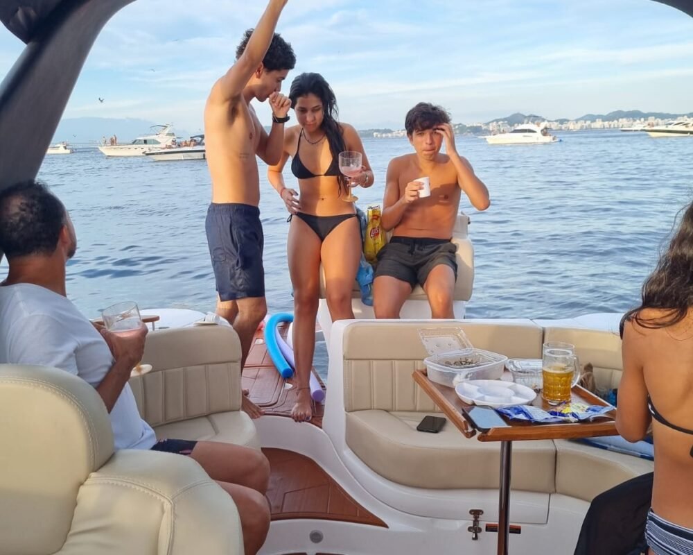 Grupo de amigos aproveitando um passeio na lancha Coral 26, com bebidas e petiscos a bordo.