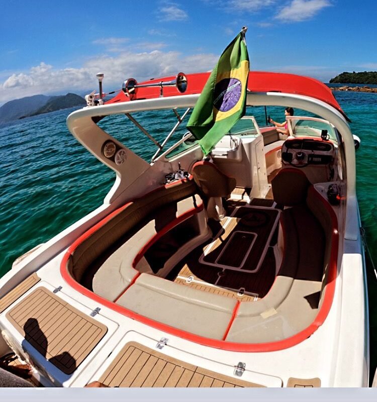 Bandeira brasileira hasteada na Lancha Futura 28, com vista para o mar azul e detalhes do deck.