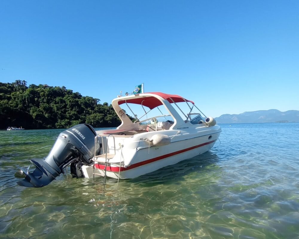 Lancha Futura 28 flutuando em águas cristalinas de Angra dos Reis, com vegetação ao fundo e céu limpo.