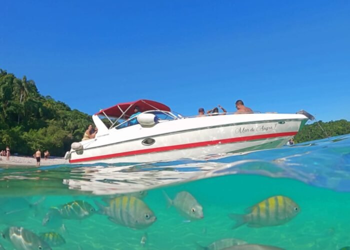 Lancha Futura 28 em um cenário paradisíaco de Angra dos Reis, com peixes tropicais visíveis na água cristalina.