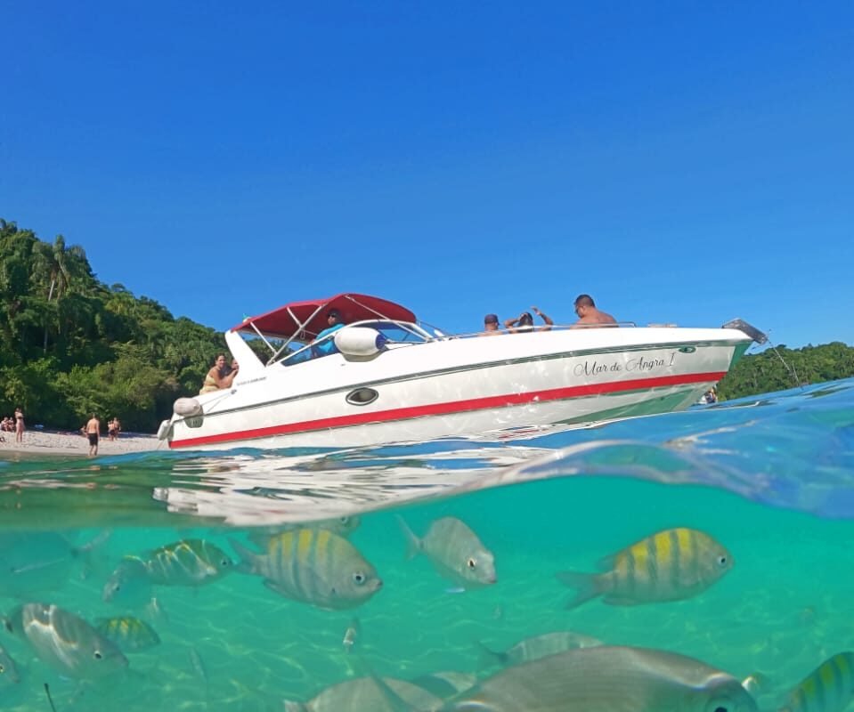 Lancha Futura 28 em um cenário paradisíaco de Angra dos Reis, com peixes tropicais visíveis na água cristalina.