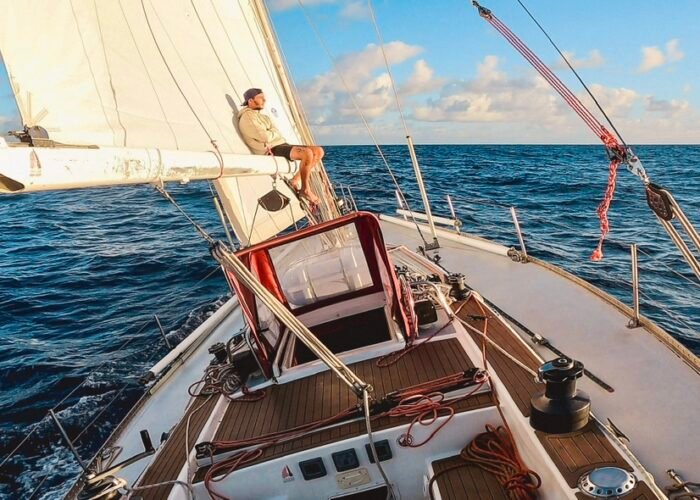 Passageiro relaxando na proa do veleiro Bruce Farr 44 enquanto navega em mar aberto.