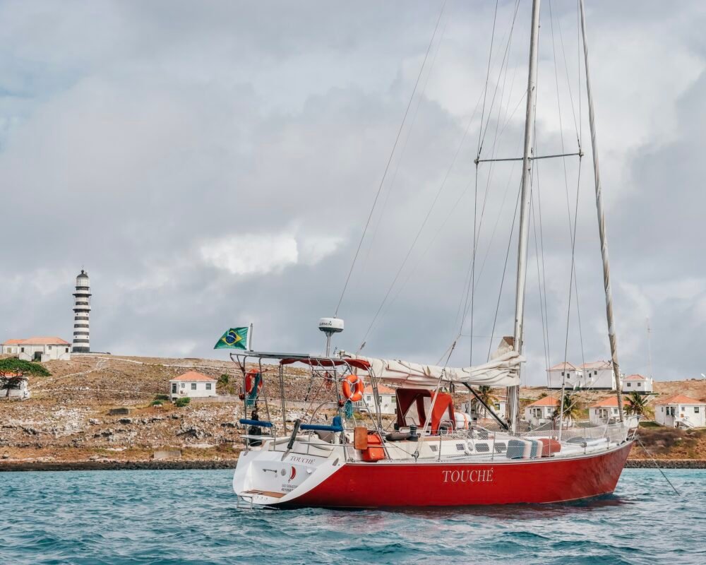 Veleiro Bruce Farr 44 ancorado próximo a uma ilha com farol ao fundo.