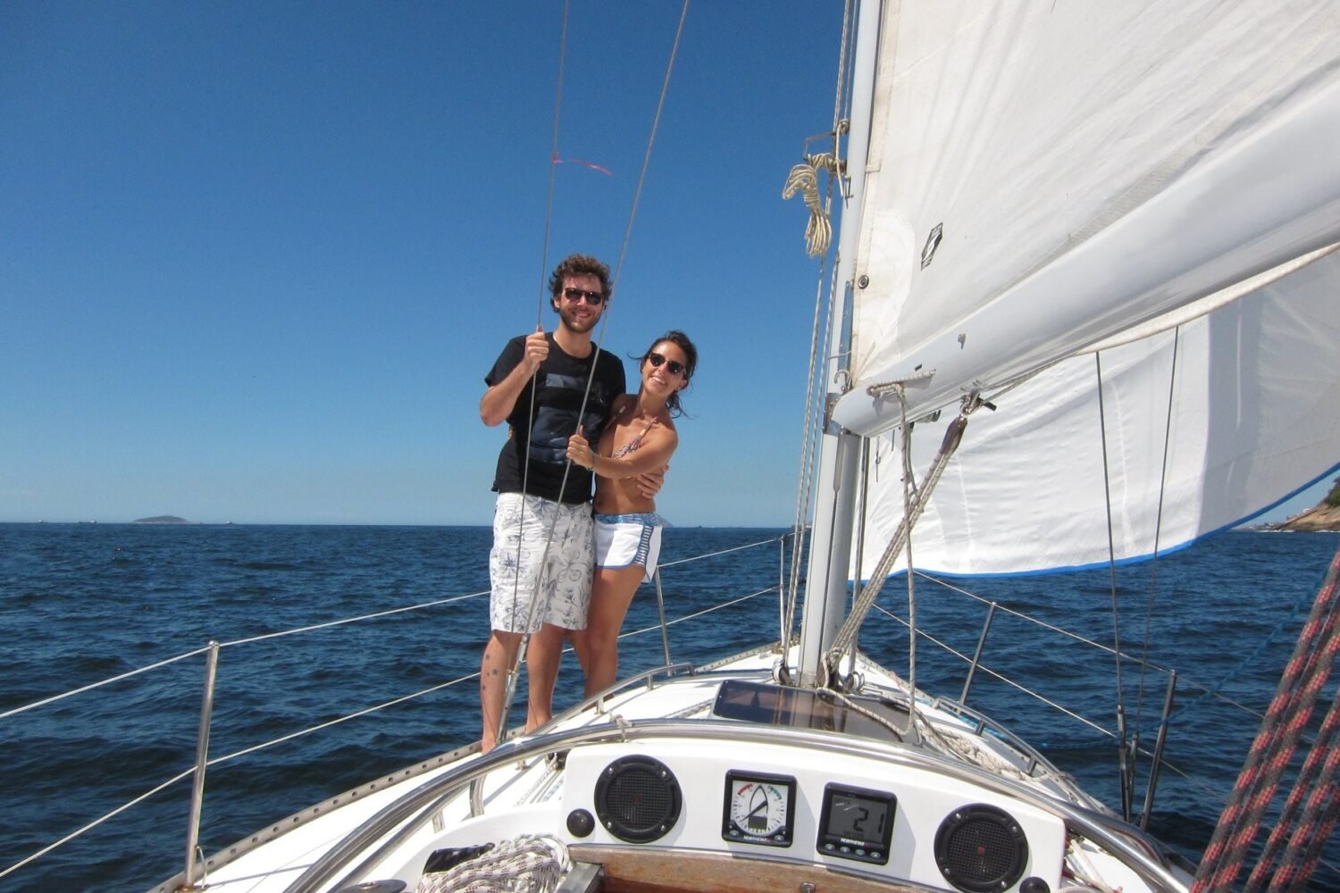 Casal navegando e aproveitando as paisagens naturais a bordo do passeio de veleiro Peterson 33 no Rio de Janeiro.