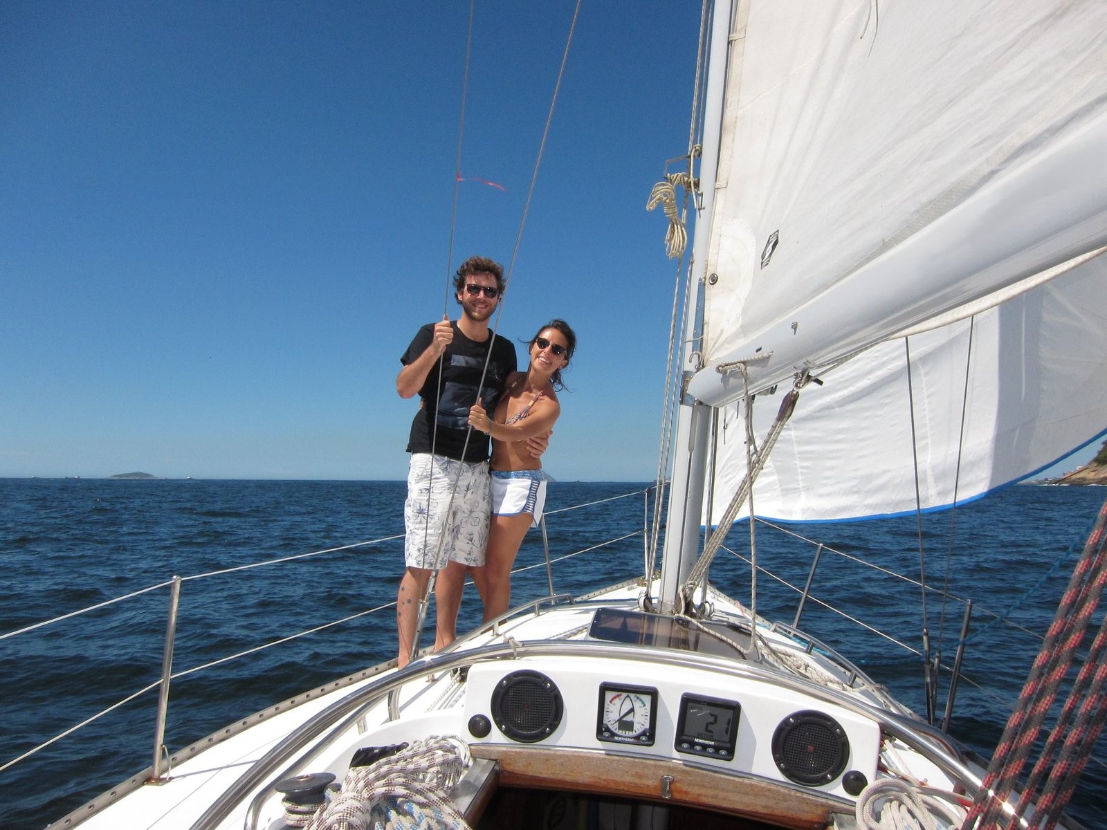 Casal navegando e aproveitando as paisagens naturais a bordo do passeio de veleiro Peterson 33 no Rio de Janeiro.