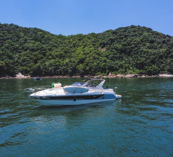 Vista lateral da lancha ancorada em uma praia paradisíaca do Guarujá, ideal para passeios privativos.