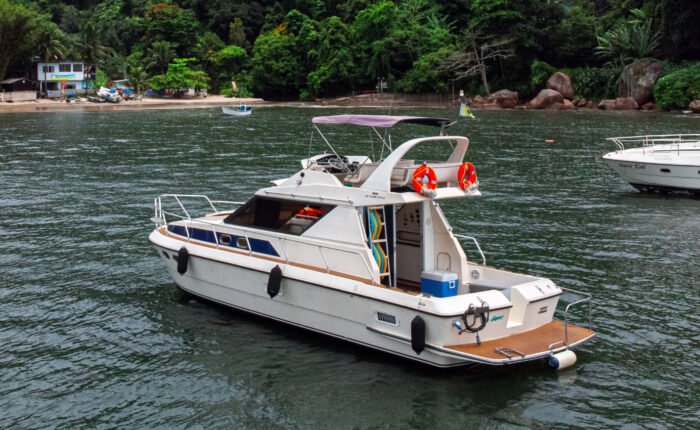 Lancha Oceanic 36 navegando em águas calmas próximas à costa do Guarujá, com vegetação exuberante ao fundo.