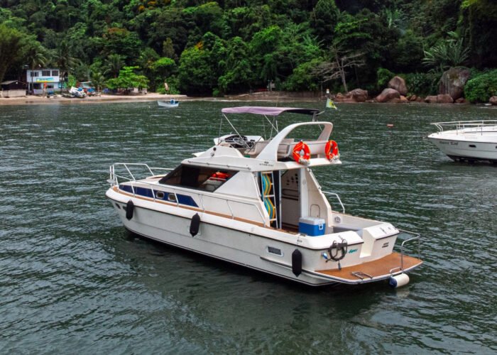 Lancha Oceanic 36 navegando em águas calmas próximas à costa do Guarujá, com vegetação exuberante ao fundo.