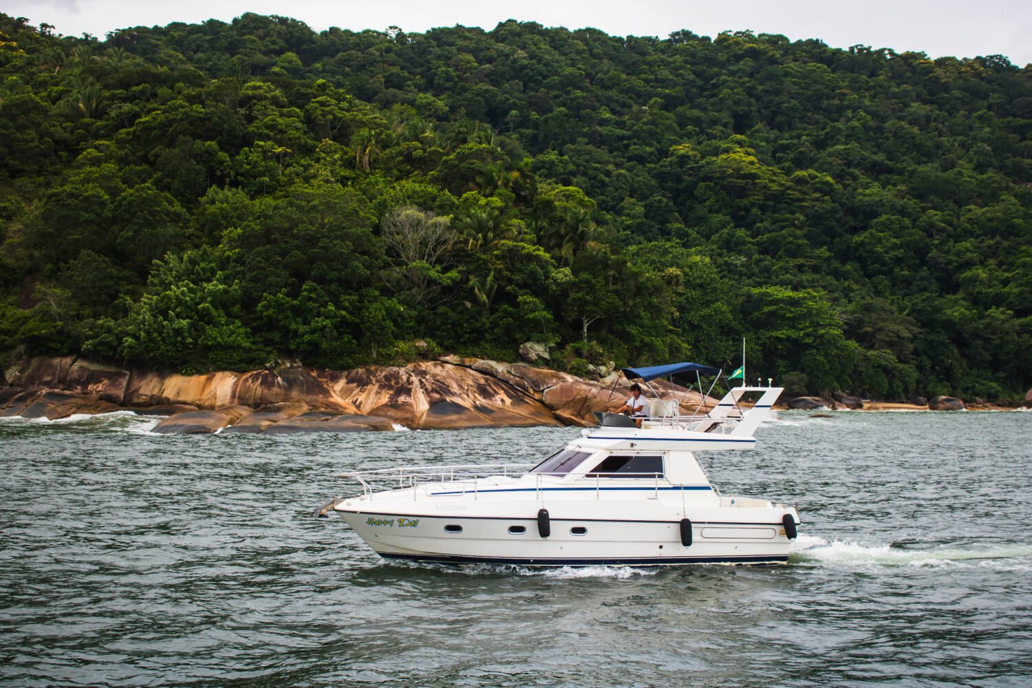 Vista lateral da Lancha Sea Baron 38 em movimento nas águas do Guarujá, cercada por paisagens naturais.