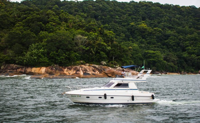 Vista lateral da Lancha Sea Baron 38 em movimento nas águas do Guarujá, cercada por paisagens naturais.