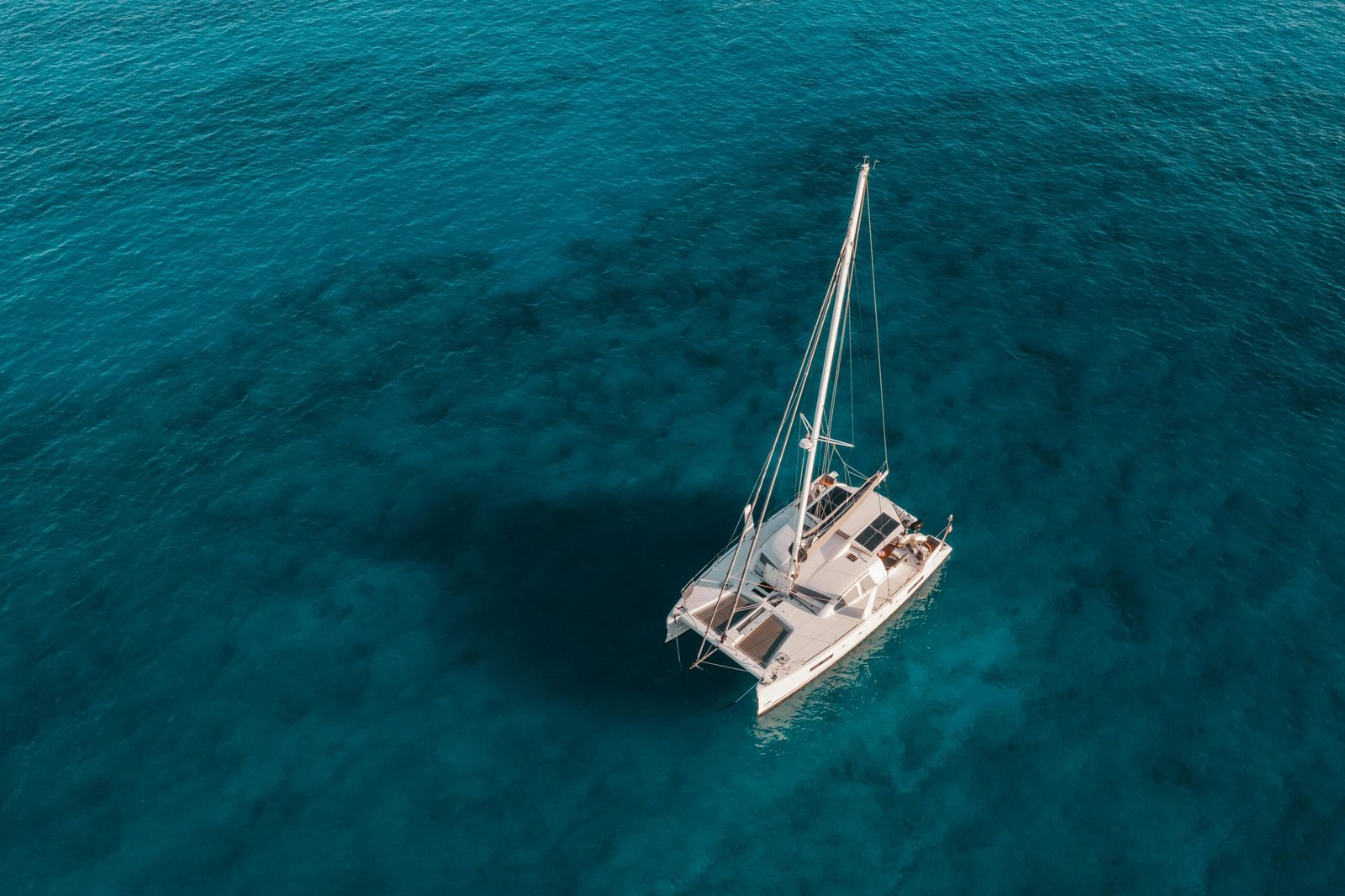 Aluguel de catamarã para um passeio inesquecível em águas cristalinas, com vista aérea da embarcação navegando no mar.