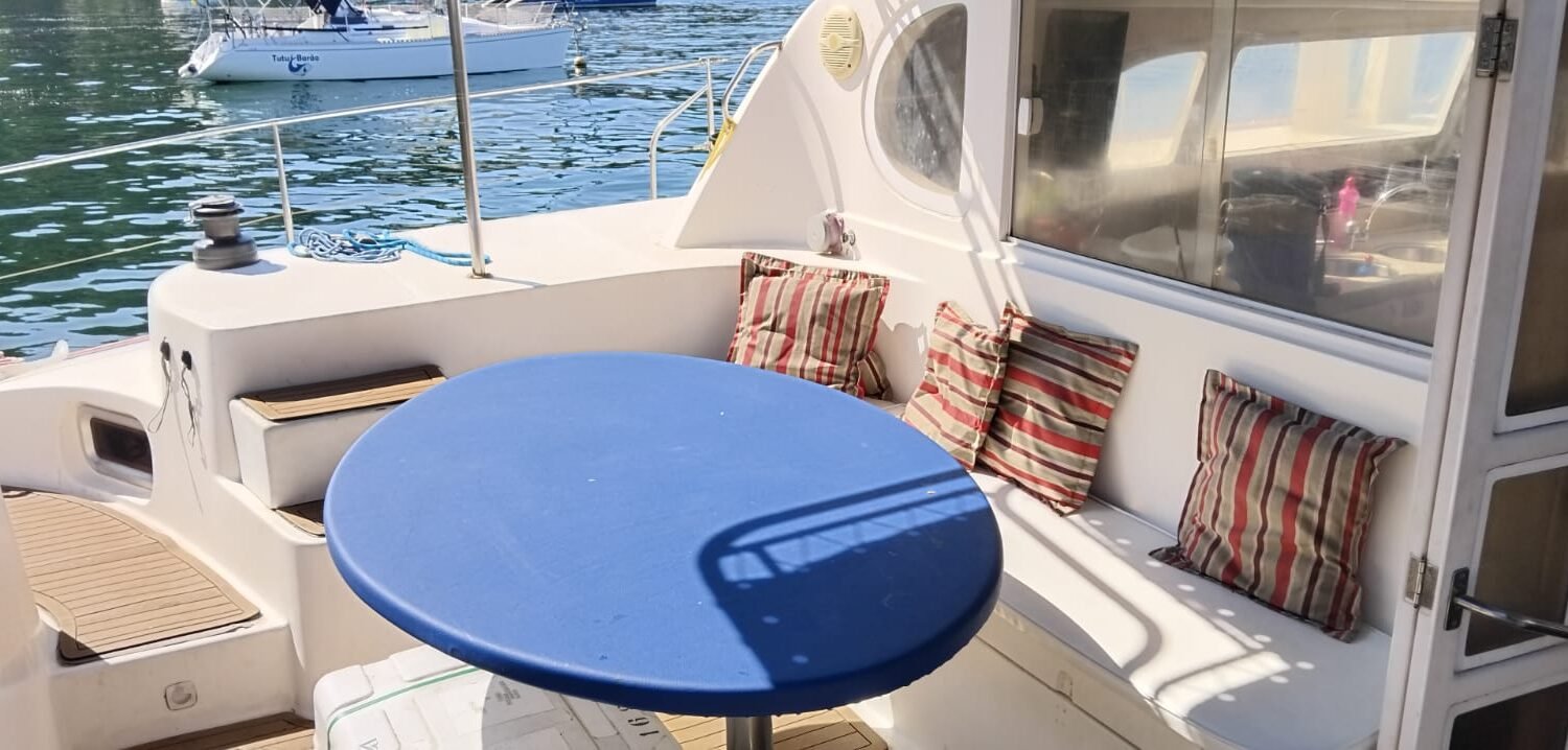 Área externa do Catamarã Dolphin 46 com mesa redonda e assentos acolchoados
