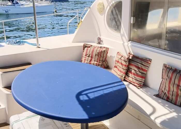 Área externa do Catamarã Dolphin 46 com mesa redonda e assentos acolchoados