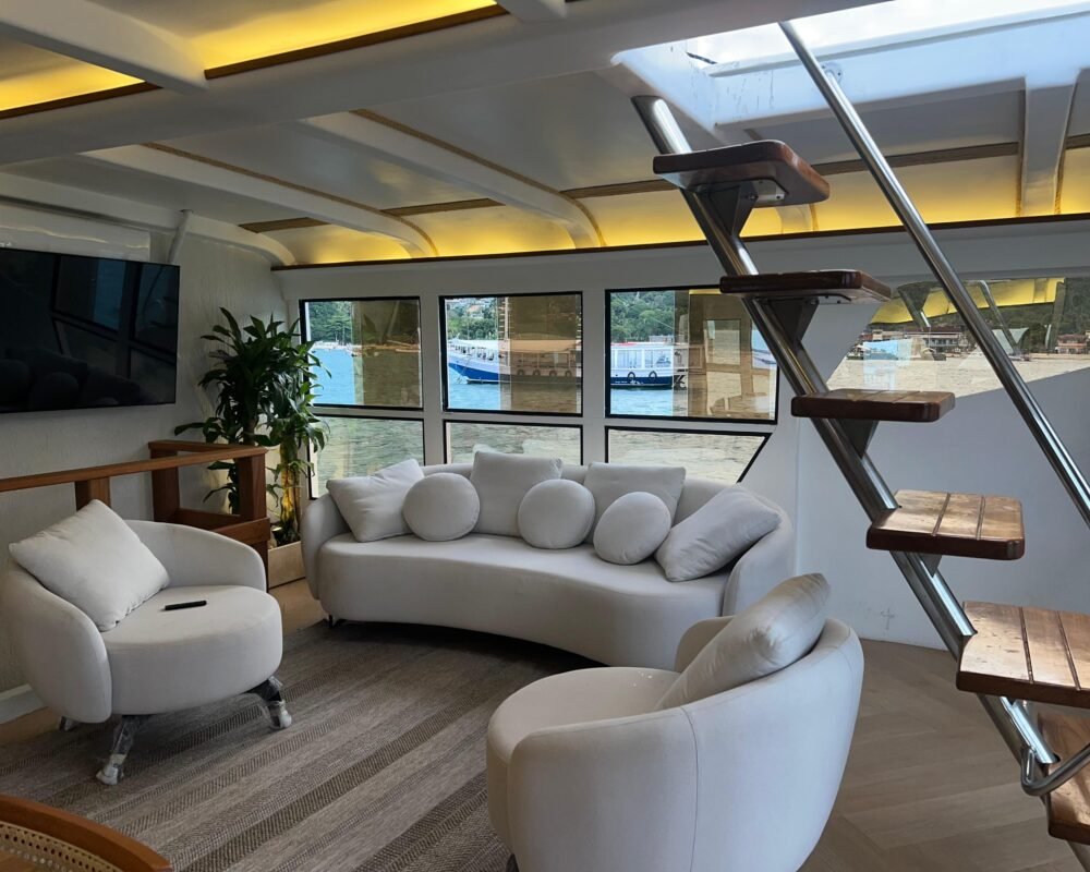 Sala de estar do Catamarã Artesanal com TV e sofás, disponível para aluguel em Angra dos Reis.