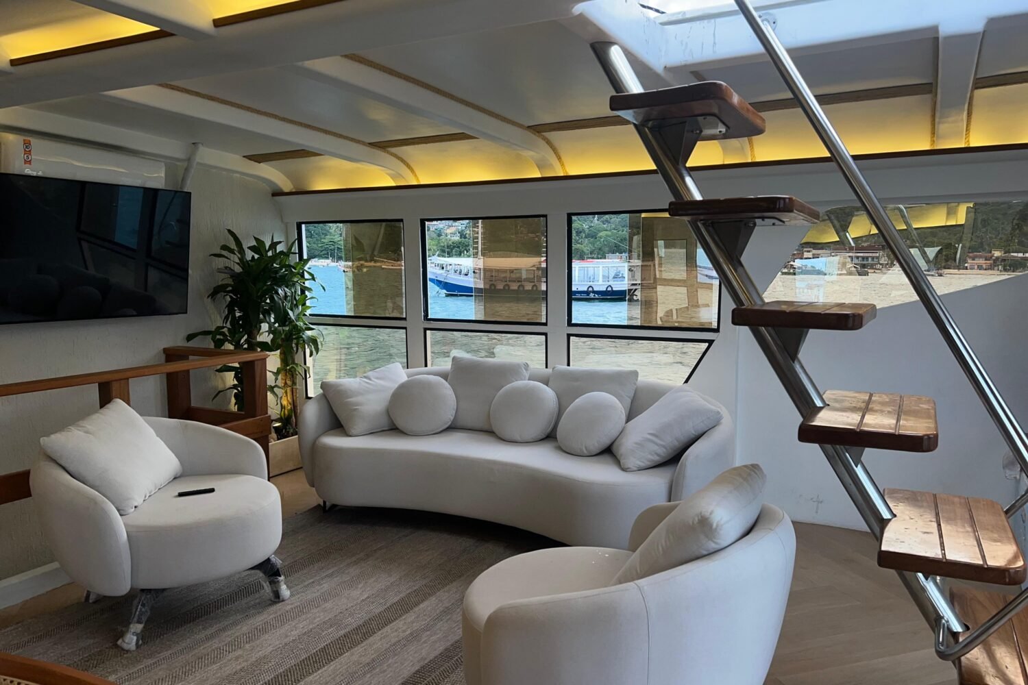 Sala de estar do Catamarã Artesanal com TV e sofás, disponível para aluguel em Angra dos Reis.