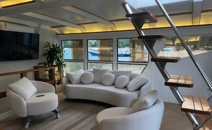 Sala de estar do Catamarã Artesanal com TV e sofás, disponível para aluguel em Angra dos Reis.
