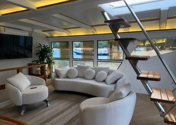 Sala de estar do Catamarã Artesanal com TV e sofás, disponível para aluguel em Angra dos Reis.