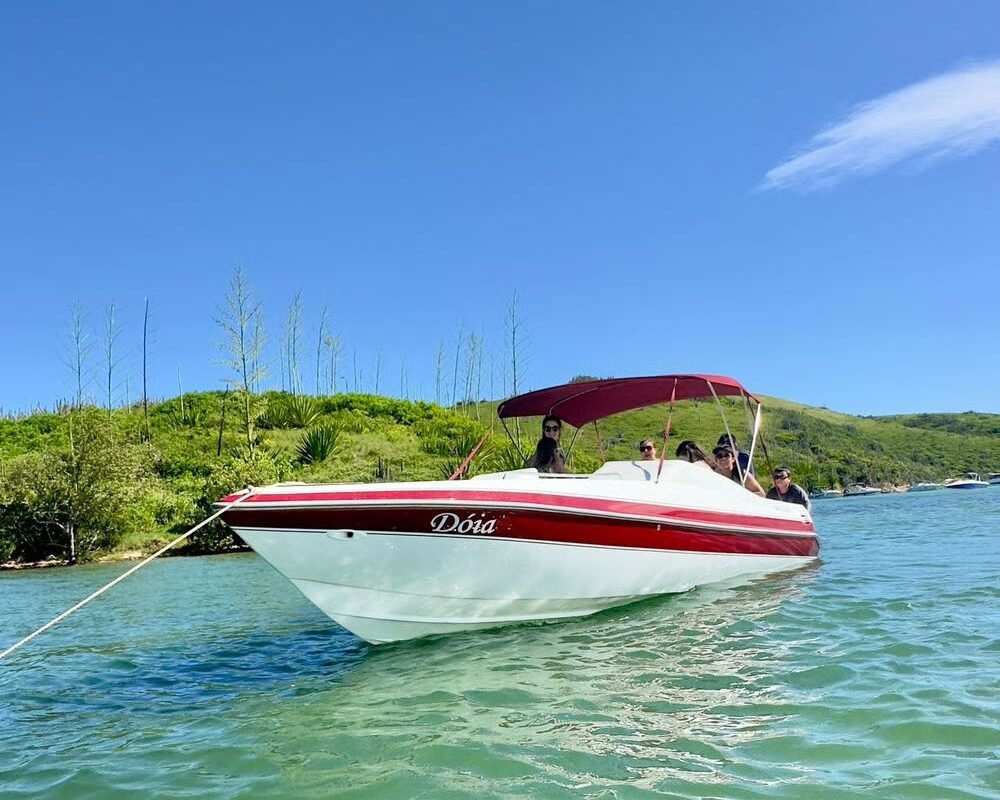 Lancha Real 220 Dóia navegando em Cabo Frio com grupo de passageiros a bordo.